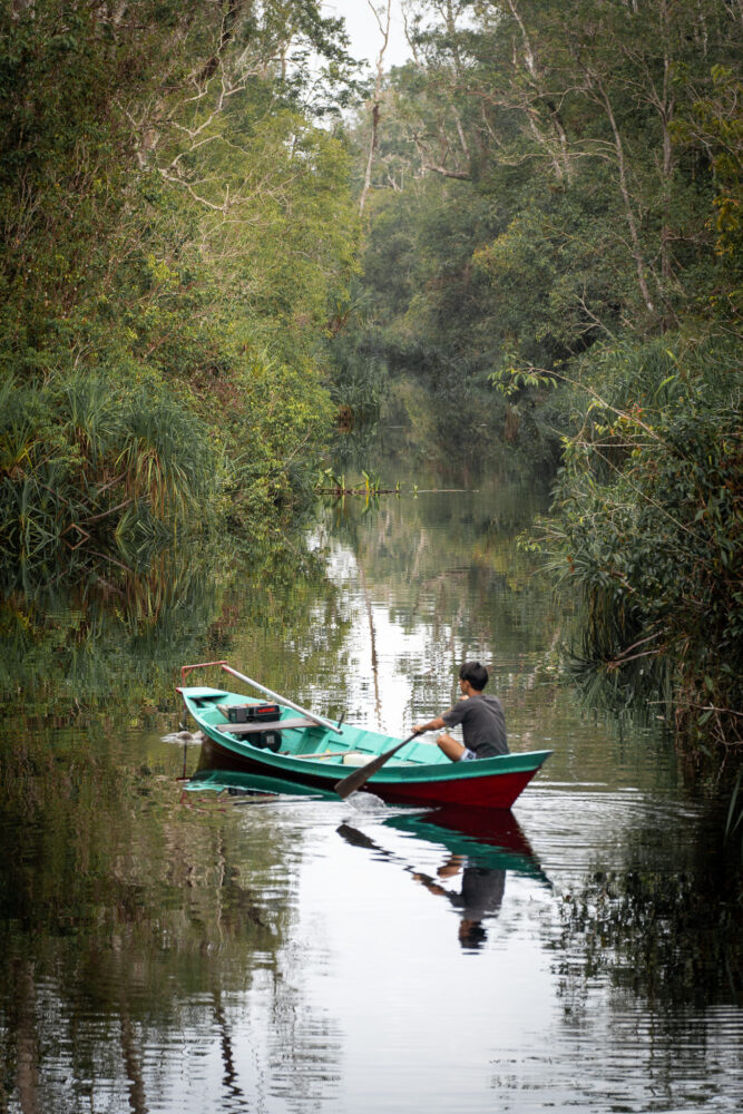 a man paddles a small boat through the river