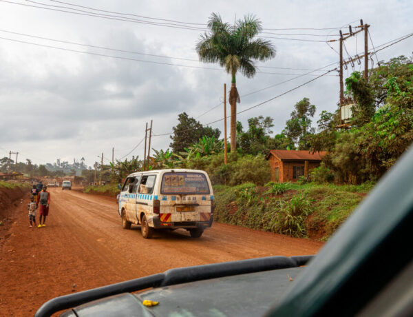 A van drives in front of us on a red clay road in Uganda