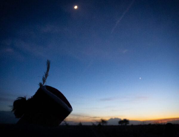 nighttime photo of man wearing a hat with a feather in it