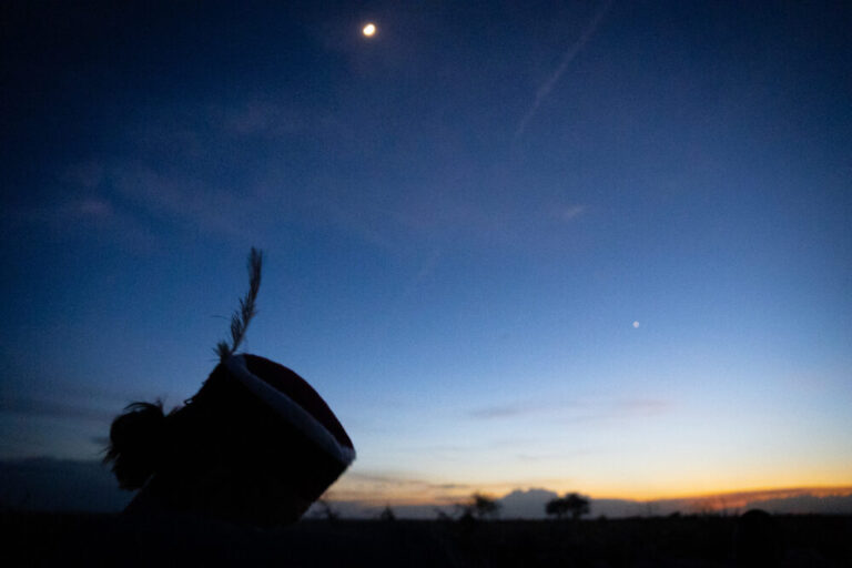 nighttime photo of man wearing a hat with a feather in it