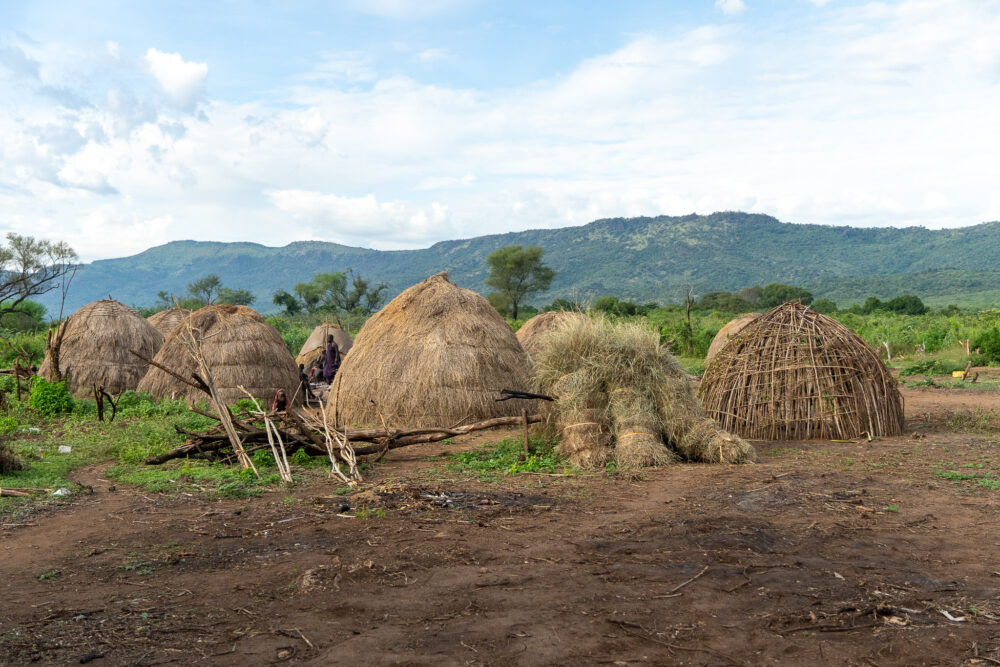 a collection of woven huts in the green landscape of Ethiopia