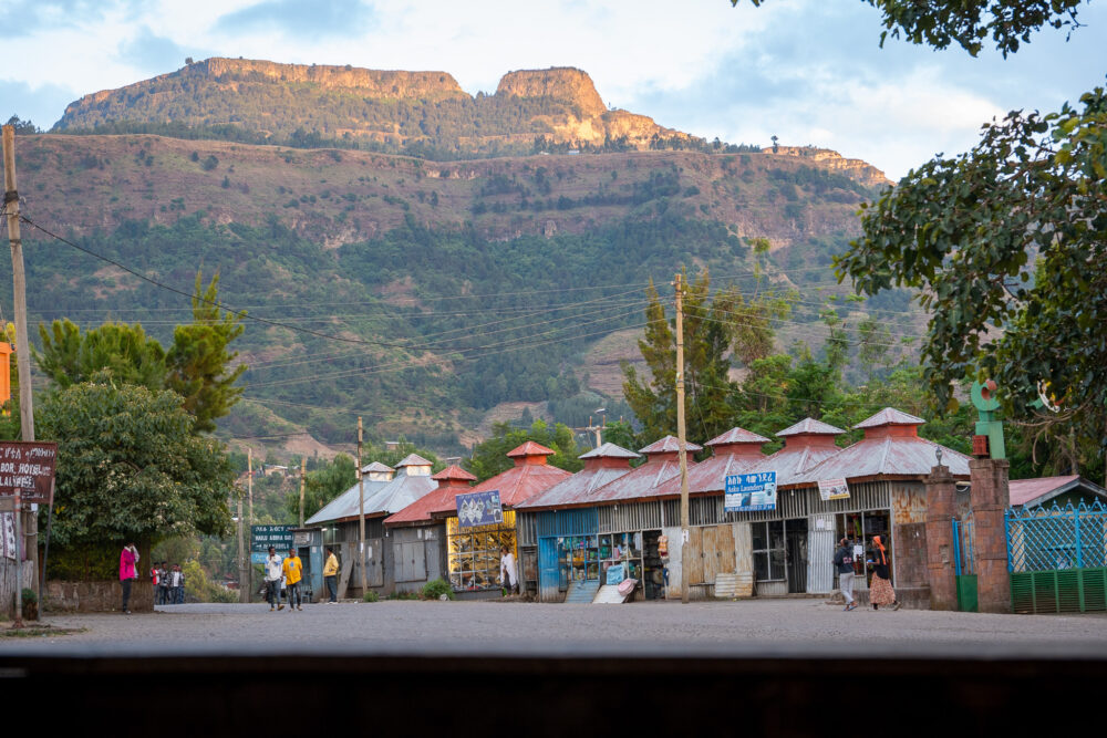 the town of lalibela with red roofed shops on the roadside with mountains in the background