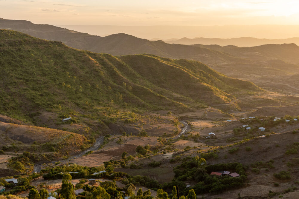 rolling hills with a village in the valley at sunset