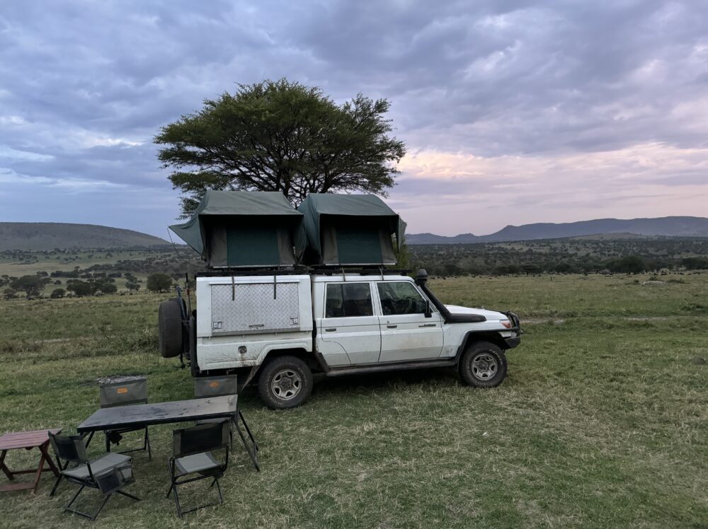 a white landcruiser with two tents on top during sunset