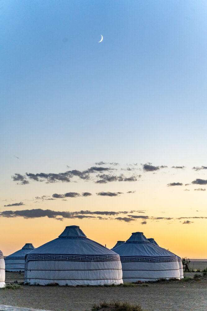 3 gers at sunset with the moon above them