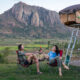 a couple drinking wine in camp chairs with car camper behind them
