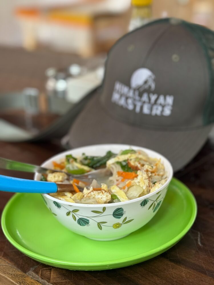 Bowl of noodle in Nepal with our himalayan masters hat in the back