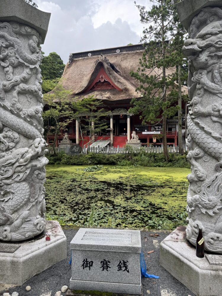 A view of a shinto temple behind a lilypad filled lake 