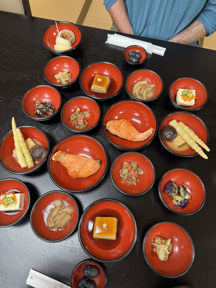 An array of bright red bowls all serving dishes like Salmon and sesame tofu 