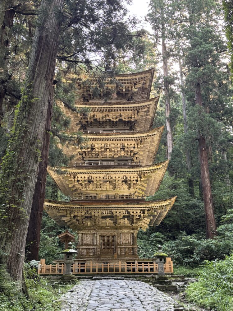 A tall golden pagoda sitting in a forest