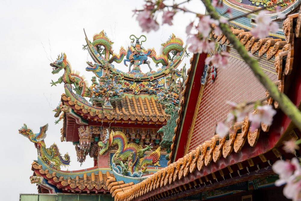 top of a Taiwanese temple framed bycherry blossoms 