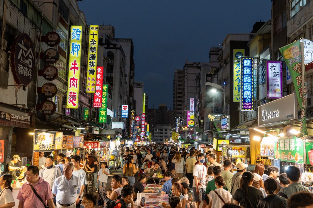 crowd at a night market with neon lights 