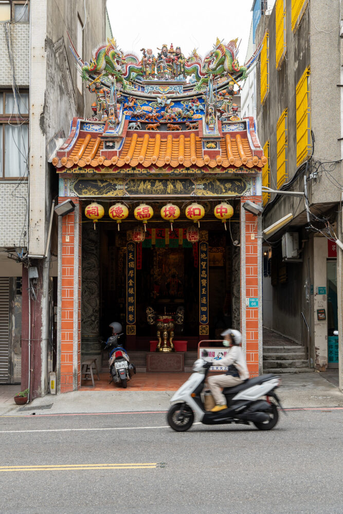 Scooter drives in front of a colorful Taiwanese temple 