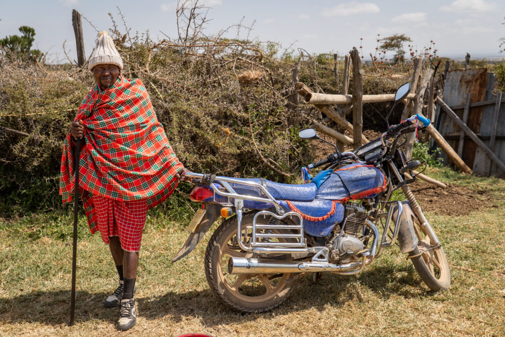 A masai man poses by his motorcycle 