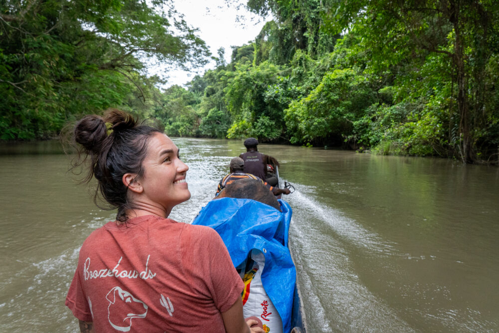 a woman sitting in a canoe in the jungle of Papua New Guinea showing  clothes to pack to PNG. 