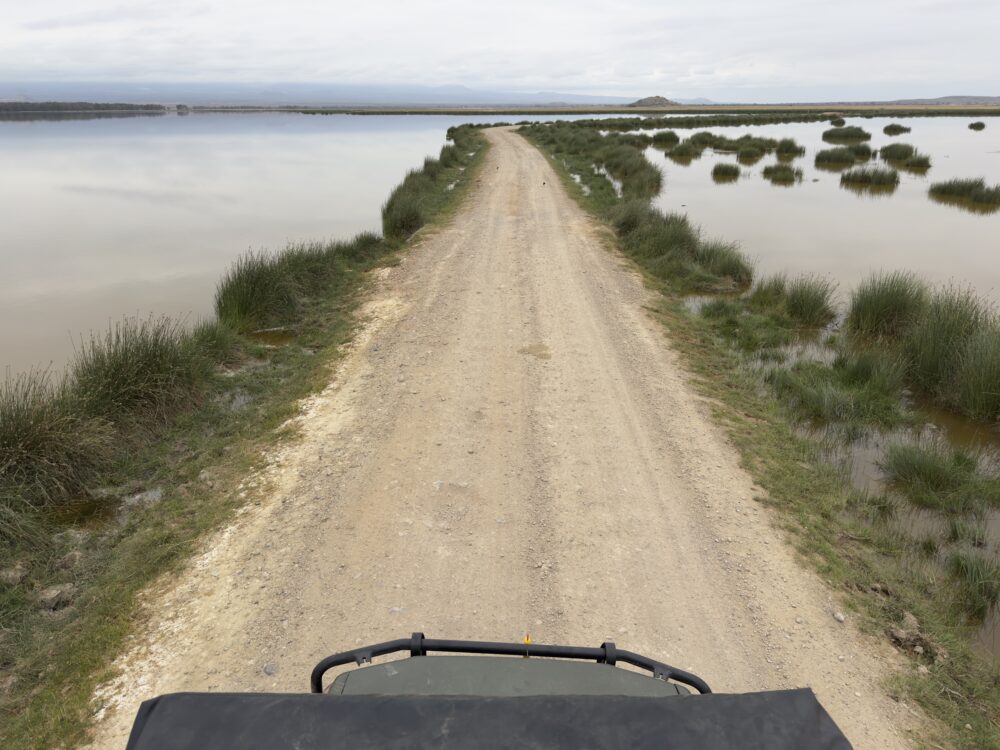 a narrow road cutting across a lake